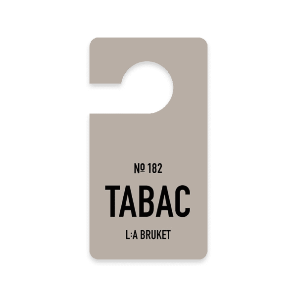 Türanhänger mit der Aufschrift 'Nº 182 TABAC L:A BRUKET' auf grauem Hintergrund.