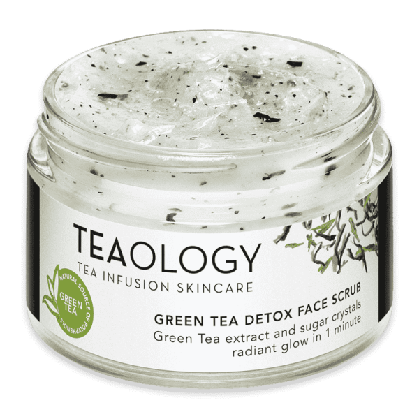 Ein Glasbehälter mit Green Tea Detox Face Scrub von Teaology, gefüllt mit einem weißen Peeling mit schwarzen Partikeln.