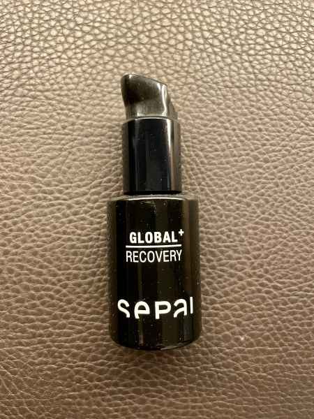 Schwarze Flasche mit der Aufschrift 'GLOBAL+ RECOVERY SEPAI' auf einer braunen Lederoberfläche.