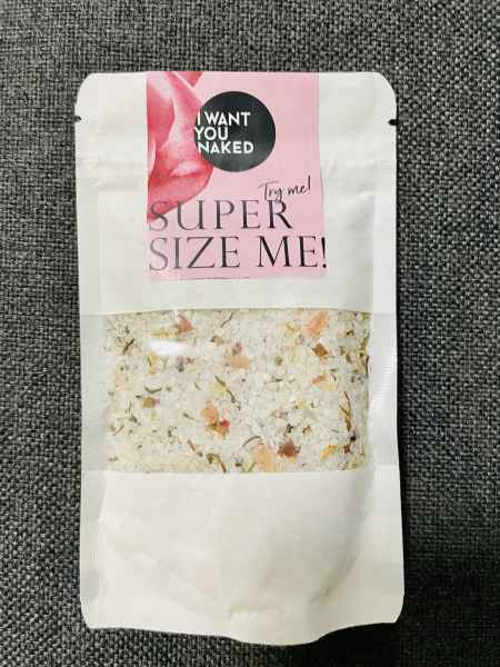 Eine Packung Badesalz mit der Aufschrift 'I WANT YOU NAKED SUPER SIZE ME!' auf einem grauen Hintergrund.