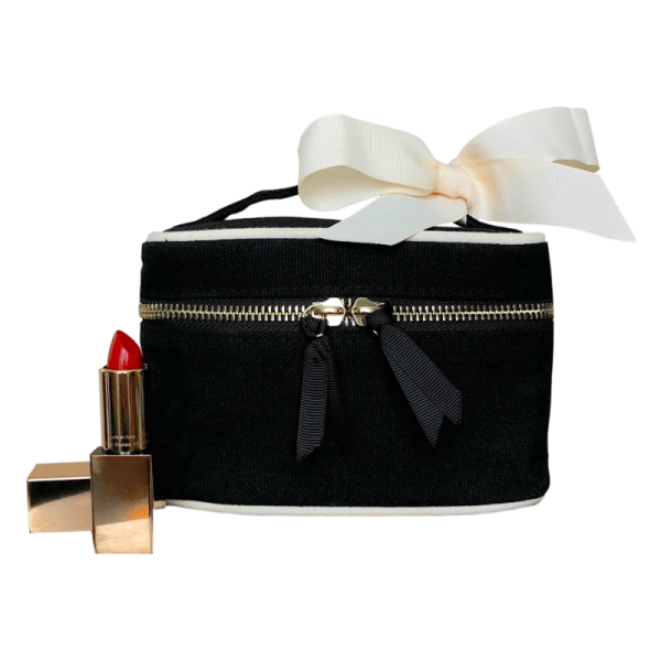 Schwarze Kosmetiktasche mit weißer Schleife und rotem Lippenstift.
