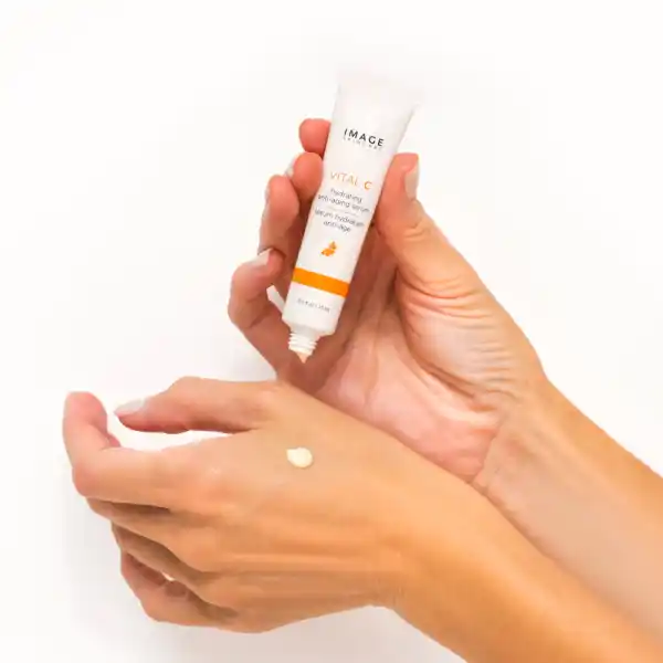 Hände tragen VITAL C feuchtigkeitsspendendes Anti-Aging-Serum von Image Skincare auf.